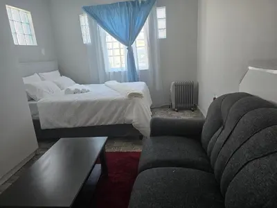 a small bedroom with a bed and a couch at Cozy home away from home in Cape Town