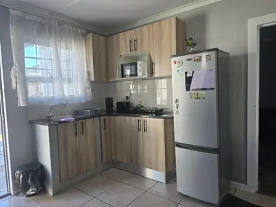 a kitchen with a white refrigerator and wooden cabinets at Cozy home away from home in Cape Town