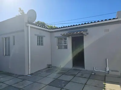 a white house with a garage and a door at Cozy home away from home in Cape Town