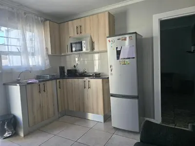 a kitchen with a white refrigerator and wooden cabinets at Cozy home away from home in Cape Town
