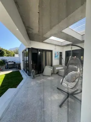 a patio with a swinging chair on a house at Helder Haven Cottage in Somerset West