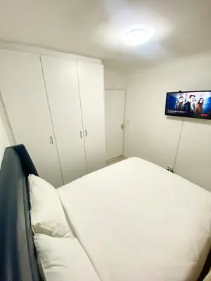 a bedroom with a bed and a flat screen tv at Chill & Cozy shared apartment with Michael in Cape Town