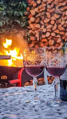 two glasses of wine sitting on a table next to a fire at La Vita e Bella in Wellington