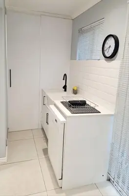 a white kitchen with a stove and a clock on the wall at Mooiloop Self Catering in Bellville