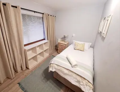 a small bedroom with a bed and a window at Mooiloop Self Catering in Bellville