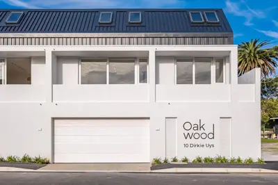 a white house with a oak wood sign on it at Whale Melody Love Hermanus in Hermanus