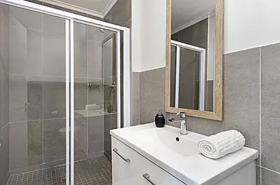 a white bathroom with a sink and a shower at Chic 1 bedroom apt in Century city in Cape Town