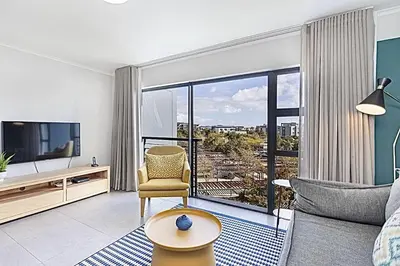 a living room with a couch and a tv at Chic 1 bedroom apt in Century city in Cape Town