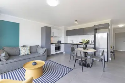a living room and kitchen with a couch and a table at Chic 1 bedroom apt in Century city in Cape Town