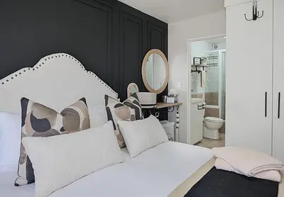 a bedroom with a white bed and a mirror at SeeHUYS Boutique Bloubergstrand Beachfront Studio in Bloubergstrand