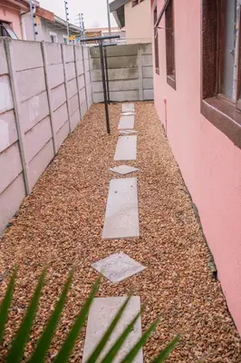 a walkway next to a pink building with stepping stones at 26 on Balfour Crescent in Silver Sands