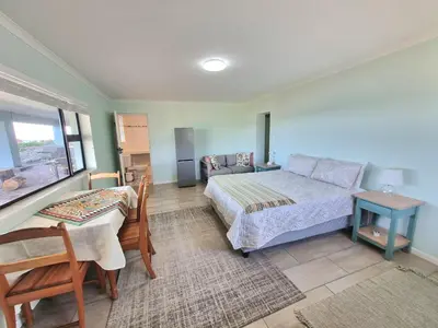 a bedroom with a bed and a table and a couch at Thalassa in Bettyʼs Bay