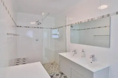 a white bathroom with a sink and a shower at Thalassa in Bettyʼs Bay
