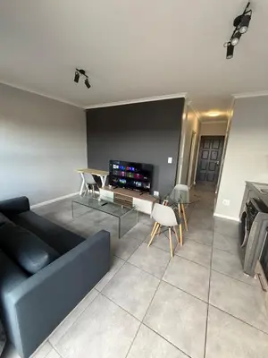 a living room with a blue couch and a tv at Table Mountain View Apartment in Cape Town