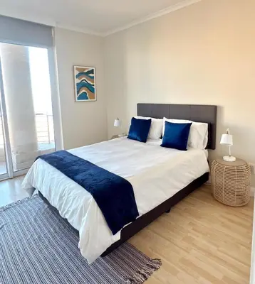 a bedroom with a large bed with blue pillows at Beautiful 2 Bedroom Apartment with Ocean Views, Bloubergstrand in Cape Town
