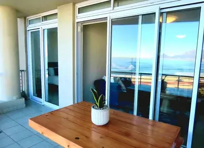 a potted plant sitting on a wooden table on a balcony at Beautiful 2 Bedroom Apartment with Ocean Views, Bloubergstrand in Cape Town