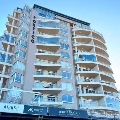 a tall apartment building with a sign on it at Beautiful 2 Bedroom Apartment with Ocean Views, Bloubergstrand in Cape Town