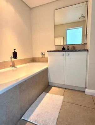 a bathroom with a large tub and a mirror at Beautiful 2 Bedroom Apartment with Ocean Views, Bloubergstrand in Cape Town