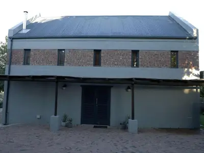 a red brick building with a black door at Gilgal Guest Accommodation in Onder-Papegaaiberg