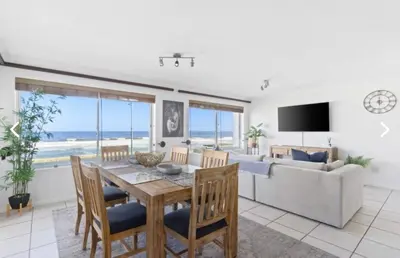 a dining room with a table and chairs and a couch at The Continental Sea Spray in Cape Town