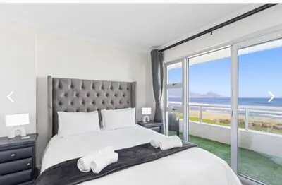 a bedroom with a large bed with a view of the ocean at The Continental Sea Spray in Cape Town