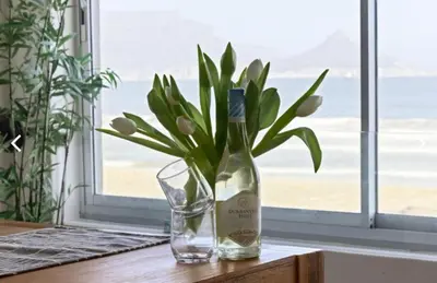 a bottle of wine sitting on a table with a glass at The Continental Sea Spray in Cape Town