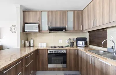 a kitchen with wooden cabinets and a stove top oven at The Continental Sea Spray in Cape Town