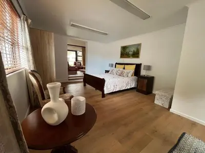a bedroom with a bed and a table with a vase on it at Central Somerset Stay in Somerset West