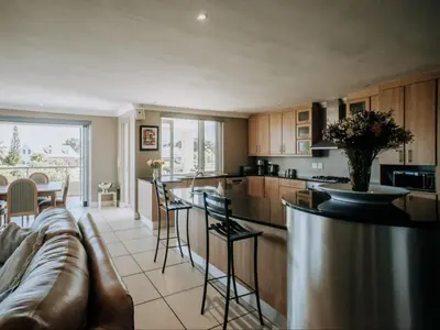a kitchen and living room with a couch and a counter at Shores Keep - Self Catering Home in Hermanus