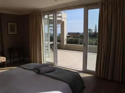 a bedroom with a large bed and a large window at Shores Keep - Self Catering Home in Hermanus