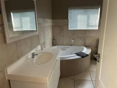 a bathroom with a bath tub and a sink at Shores Keep - Self Catering Home in Hermanus