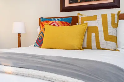 a white bed with colorful pillows at Suikerbossie 52 in Cape Town