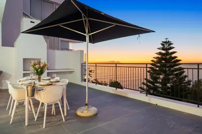 a table and chairs with an umbrella on a balcony at Suikerbossie 52 in Cape Town
