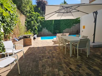 a patio with a table and chairs and an umbrella at 5 Rembrandt Guesthouse in Somerset West