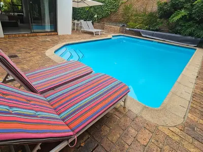 a swimming pool with two lounge chairs next to it at 5 Rembrandt Guesthouse in Somerset West