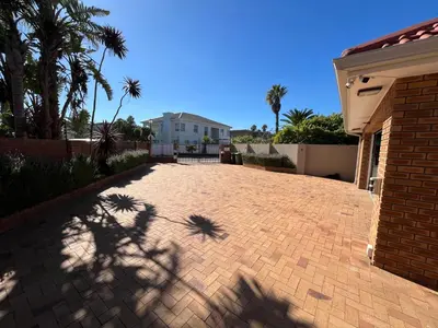a brick driveway with a house and palm trees at Sunset Breeze in Cape Town