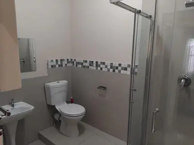 a bathroom with a toilet and a shower and a sink at Wilcuma Lodge in Plattekloof