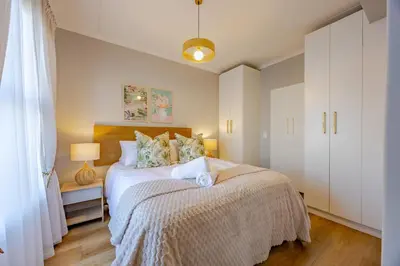 a bedroom with a bed and a white cabinet at Modern 2 bed, 2 bath, 14B- Blouberg in Bloubergstrand