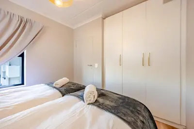 a bedroom with a bed and white cabinets at Modern 2 bed, 2 bath, 14B- Blouberg in Bloubergstrand