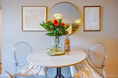 a table with a vase of flowers and a mirror at Modern 2 bed, 2 bath, 14B- Blouberg in Bloubergstrand