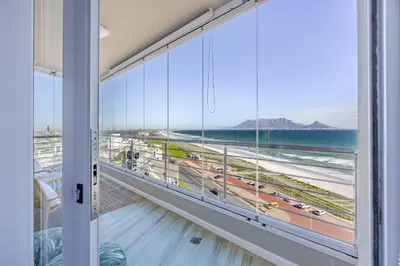 a room with a large window with a view of the beach at Luxury Beachfront-LaVista with Mountain & Ocean views in Bloubergstrand