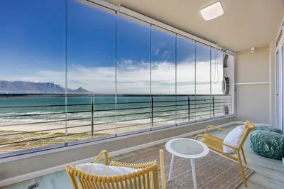 a room with a large window with a view of the ocean at Luxury Beachfront-LaVista with Mountain & Ocean views in Bloubergstrand