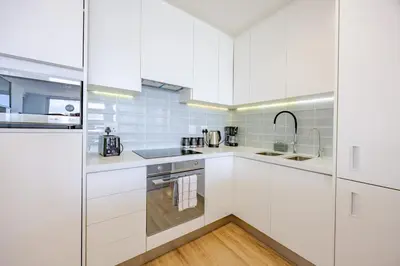 a white kitchen with white cabinets and a sink at Luxury Beachfront-LaVista with Mountain & Ocean views in Bloubergstrand