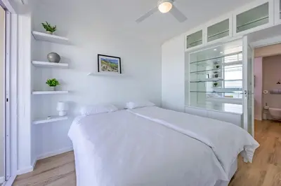 a white bedroom with a white bed and a window at Luxury Beachfront-LaVista with Mountain & Ocean views in Bloubergstrand