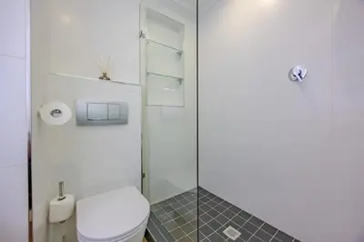 a bathroom with a toilet and a glass shower at Luxury Beachfront-LaVista with Mountain & Ocean views in Bloubergstrand