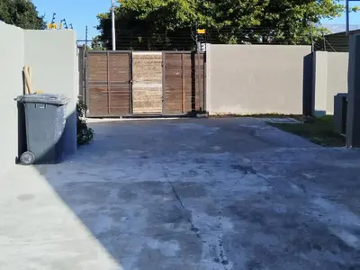 a parking lot with a fence and a trash can at Eneco Lodge in Cape Town