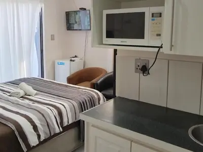 a small room with a bed and a microwave at Eneco Lodge in Cape Town