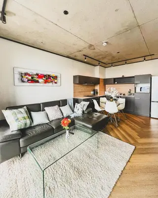 a living room with a black couch and a table at Olive Apartment on Bridgewaters in Cape Town