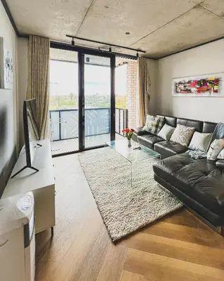 a living room with a couch and a glass table at Olive Apartment on Bridgewaters in Cape Town