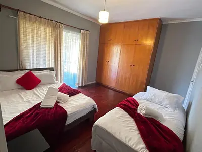 a bedroom with two beds and a wooden cabinet at M&D Guest House in Bellville